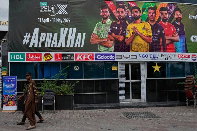Workers walk past an advertisement board of Pakistan Super League T20 tournament in Rawalpindi on Friday