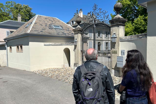 The backs of people outside a gated property