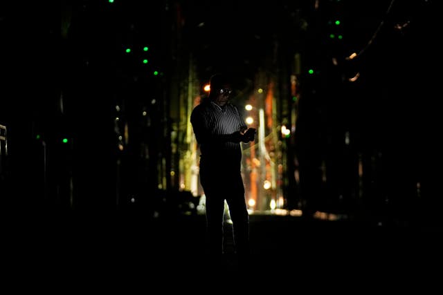 A man checks his mobile phone during a blackout in Jammu