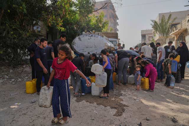 People carry containers of water in a refugee camp