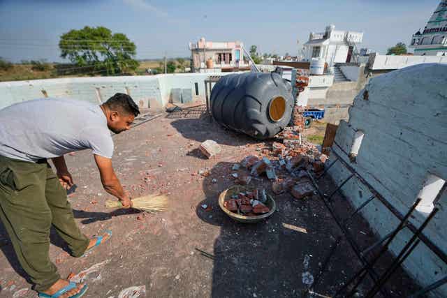 A villager cleans the roof of his house