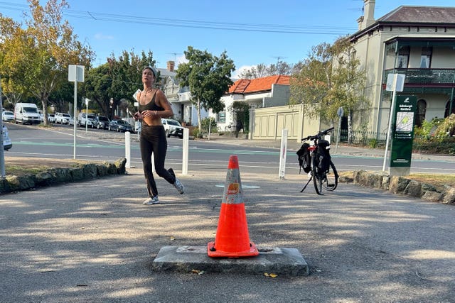 A person jogs near a traffic cone where a monument of British explorer Captain James Cook once stood before it was removed following continued vandalism at a park Melbourne, Australia