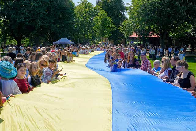 People from Ukraine hold a giant Ukrainian flag during a family meeting with their Eurovision band Ziferblat in a park in Basel as part of the 69th Eurovision Song Contest week