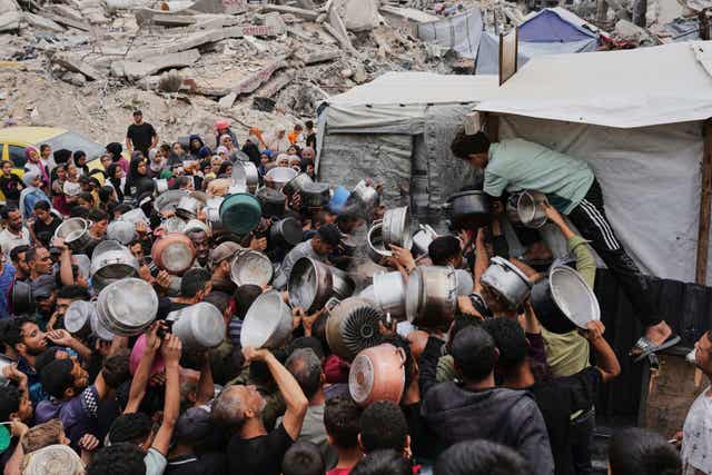 Palestinians struggle to get donated food at a community kitchen in Jabalia