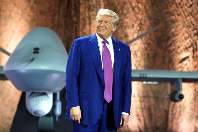 President Donald Trump smiles backdropped by an MQ-9 Reaper drone before addressing military personnel at the Al Udeid Air Base in Doha, Qatar