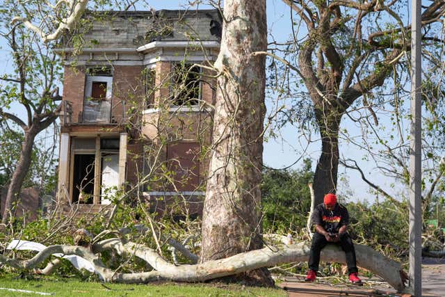 A man sits down near a downed tree