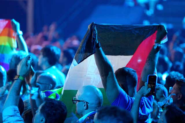 A Palestinian flag is held up in the audience as Yuval Raphael from Israel performs during a dress rehearsal on Friday