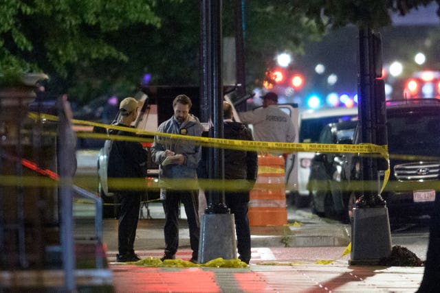 Law enforcement officials standing within a cordon marked out with yellow crime scene tape