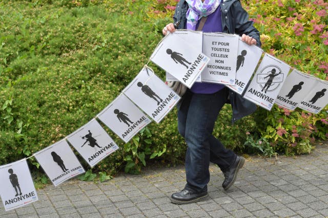 A person holds a banner representing anonymous victims during a demonstration
