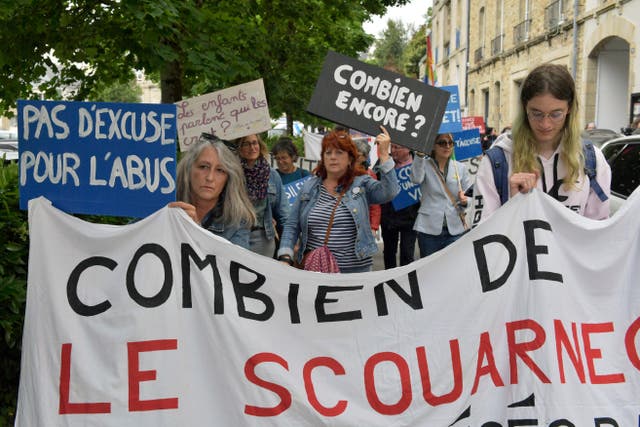 People demonstrate with a banner reading: 'How many Le Scouarnec'