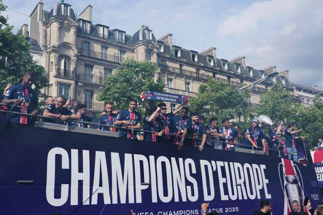 Paris St Germain players present the Champions League trophy to supporters during a parade on the Champs Elysees