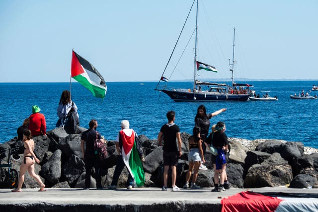 People watch a boat setting sail for Gaza