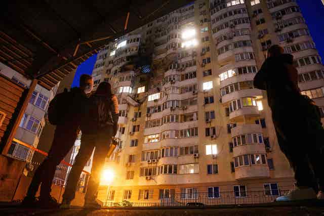 People look up at damage to a multi-storey building in Kyiv