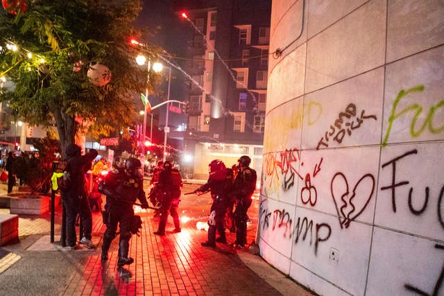 Police take cover from projectiles during protests over the Trump administration’s immigration raids in Los Angeles