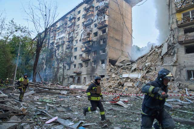 Rescuers run to a shelter to hide from a Russian air raid