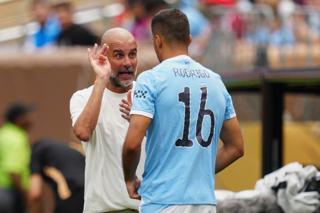 Manchester City manager Pep Guardiola talks to Rodri