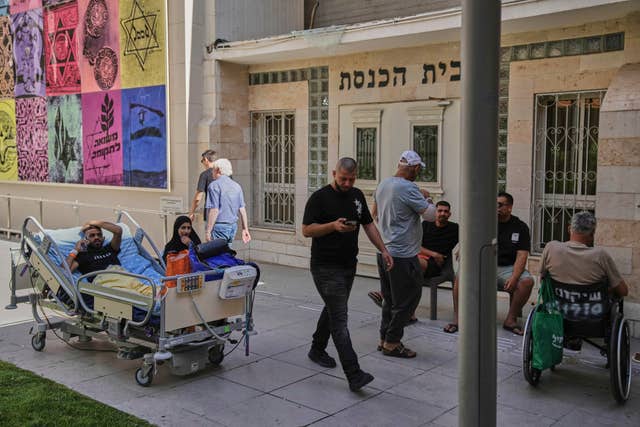 Patients rest outdoors after a building at the Soroka hospital complex was hit by a missile fired from Iran in Be’er Sheva, Israel