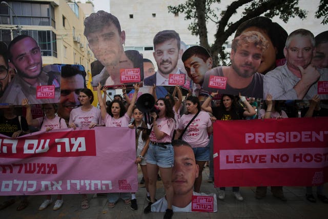 People holding up signs featuring the faces of hostages