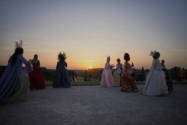 Costumed guests arrive in the gardens of Versailles