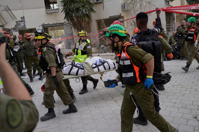 Israeli soldiers and rescue workers carry a body from a residential building destroyed by an Iranian missile strike