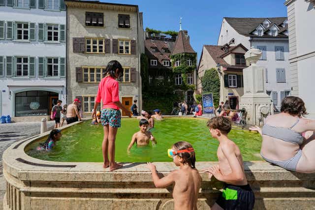 Young people take a bath at a fountain during a heat wave in the city centre of Basel,