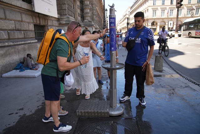 People use a street water fountain during a heatwave