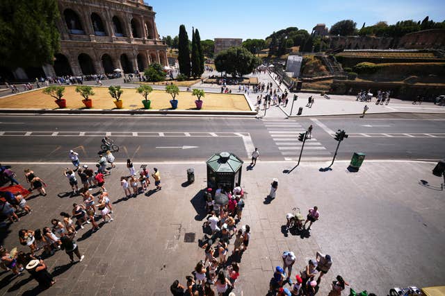 People stand in a line in front of a public fresh drinking water kiosk to drink and refill their water bottles, in Rome,