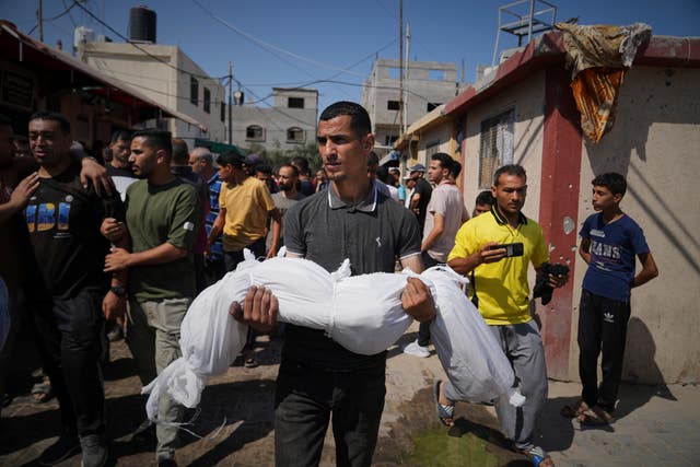 A man carries the shrouded body of a child