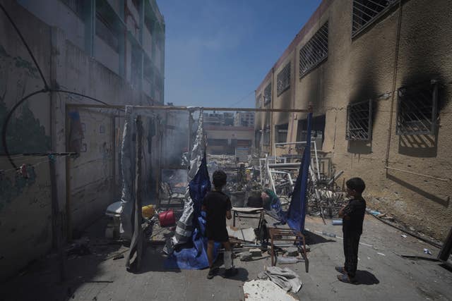 Palestinians children look at the destruction at a school used as a shelter