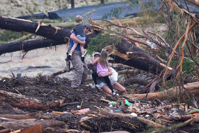 A woman falls while climbing with others over debris on a bridge atop the Guadalupe River after a flash flood swept through the area