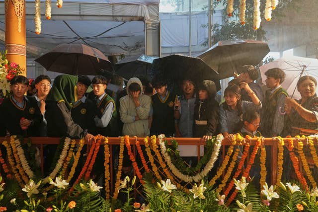 Tibetan school children wait in the rain for the arrival of the Dalai Lama