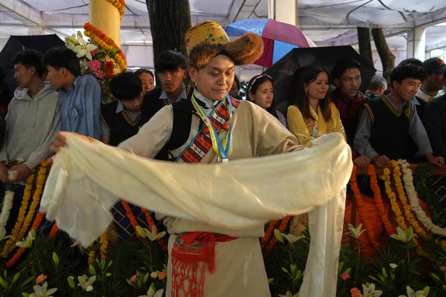 A devotee in her traditional dress folds a ceremonial offering brought for the Tibetan spiritual leader