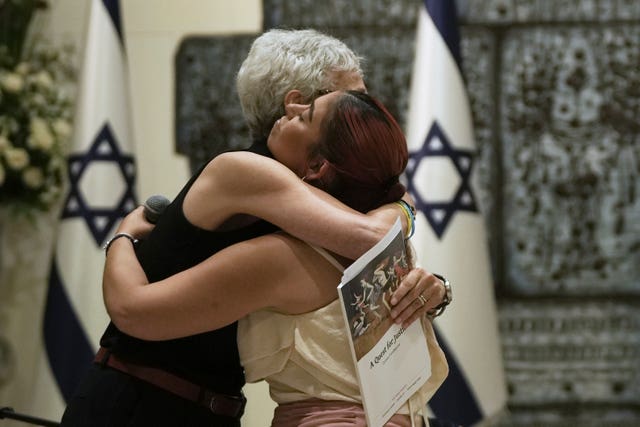 A freed hostage is embraced after her testimony at a ceremony presenting the Dinah Project report