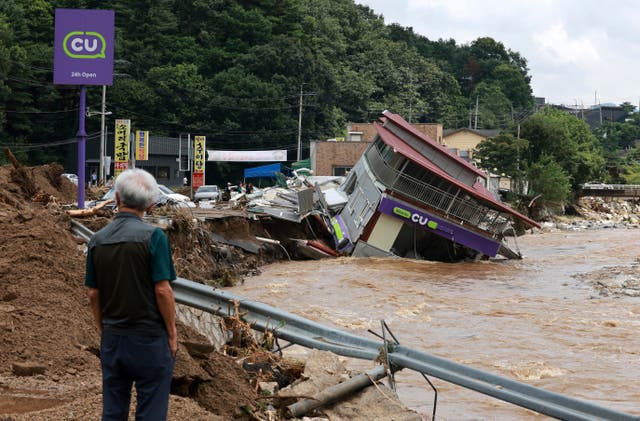Buildings partially submerged in floodwater, with a man looking on