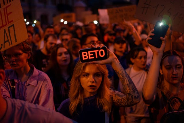 A woman holds a phone with a sign reading 'veto' during a protest against the law