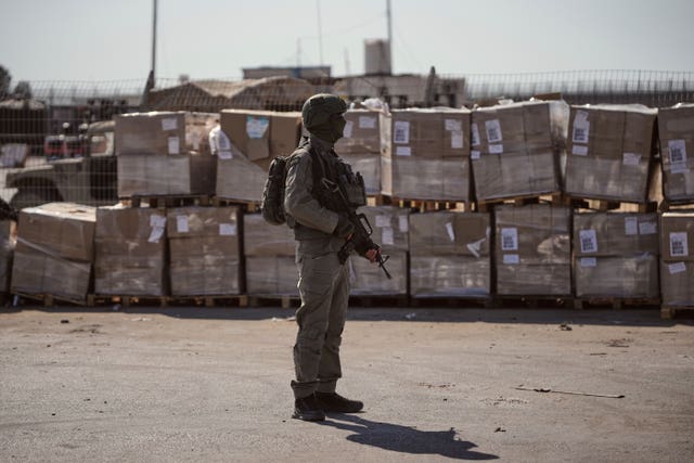An Israeli soldier stands beside humanitarian aid packages