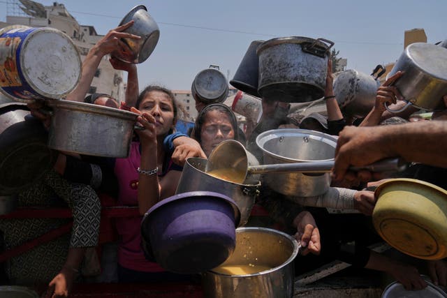 Palestinians struggle to get donated food at a community kitchen in Gaza City