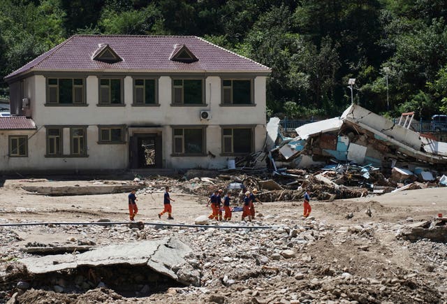 Rescuers evacuate a stranded villager, passing an area damaged by floods after heavy rains in Liulimiao Town of Huairou District on the outskirts of Beijing