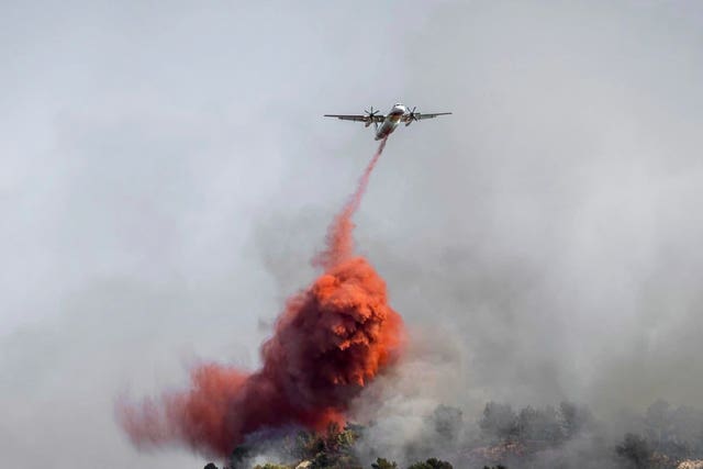 A water bomber dropping liquid on a fast-moving wildfire in a Mediterranean region of France near the Spanish border