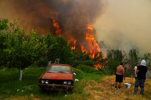 Men watch a wildfire on the outskirts of Patras, western Greece
