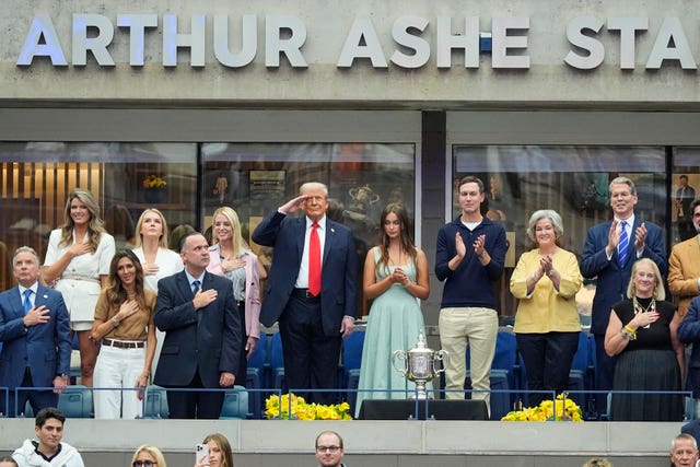 President Donald Trump, centre, salutes during the national anthem