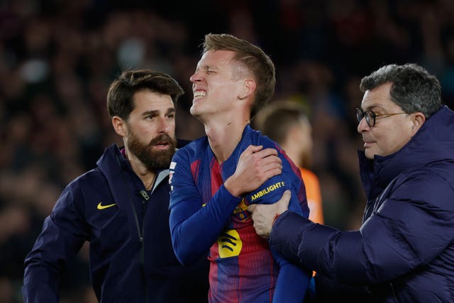 Barcelona’s Dani Olmo holds his shoulder in pain after scoring against Atletico Madrid