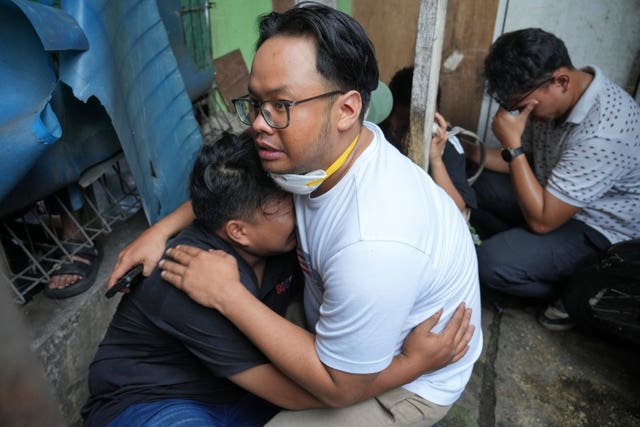 Two people comfort one another at the site of a fire in Jakarta, Indonesia