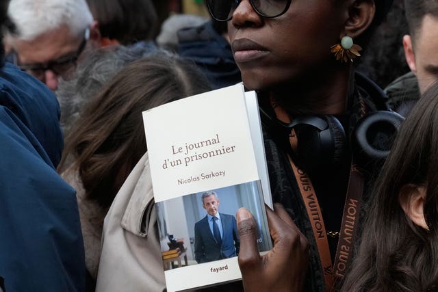 A woman holds a copy of Nicolas Sarkozy's book