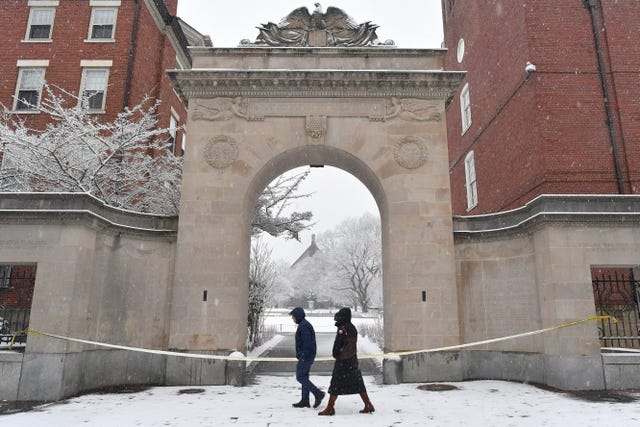 Passers-by walk past crime scene tape at an entrance to Brown University