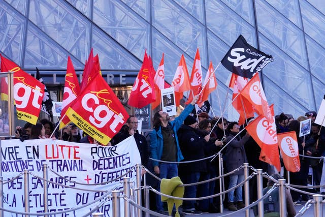 Workers hold banners outside the Louvre museum
