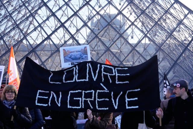 Workers hold banners outside the Louvre museum