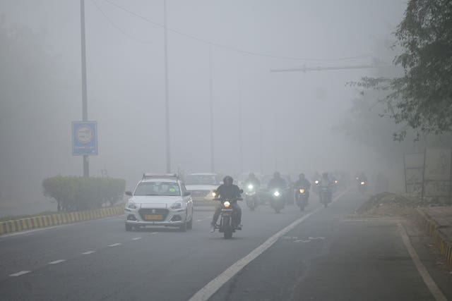 Traffic moves through dense smog
