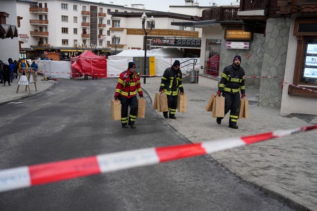 Firefighters carrying equipment near the sealed off Le Constellation bar in Crans-Montana