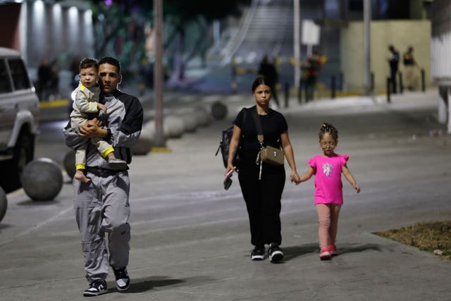 Pedestrians walk past the Miraflores presidential palace in Caracas